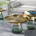 Collection de 3 tables, 1 table basse, 1 bout de canapé et 1 en métal bronze et verre vert. Toutes les tables ont une échelle différente avec un plateau en doré et un pied bouteille de verre.